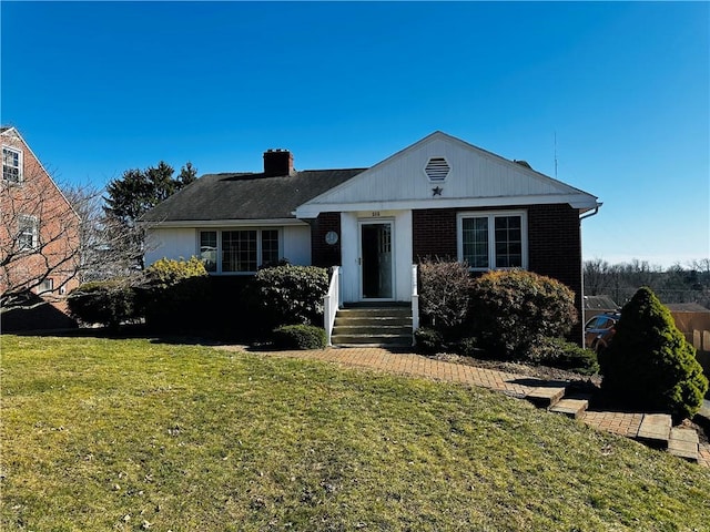 view of front of house with brick siding, a chimney, and a front lawn