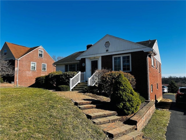 bungalow-style home with brick siding and a front yard