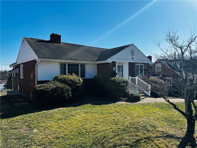 view of front of home with brick siding, a chimney, and a front lawn