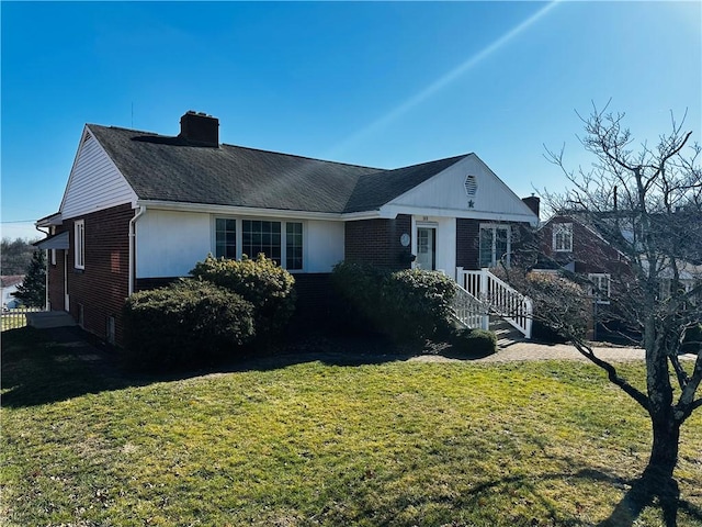 view of front facade with a front yard, brick siding, and a chimney