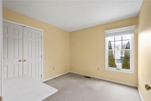 unfurnished bedroom featuring a closet, baseboards, and carpet floors