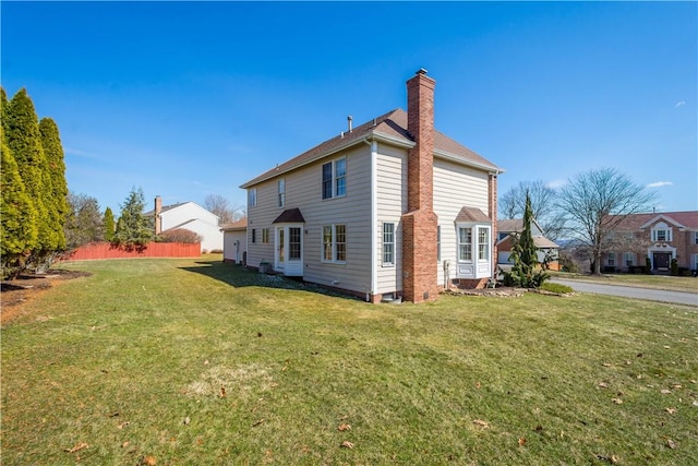 back of house with a yard, a chimney, and fence