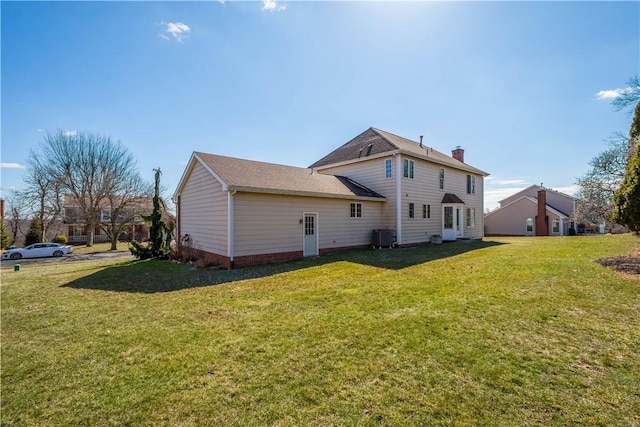 back of property featuring cooling unit, a lawn, and a chimney