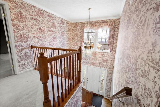 stairway with wallpapered walls, an inviting chandelier, baseboards, and ornamental molding