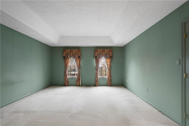 unfurnished room featuring a raised ceiling, a textured ceiling, and carpet flooring