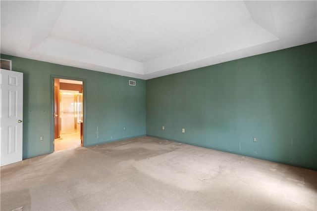 empty room featuring visible vents, carpet, and a tray ceiling