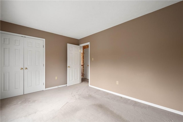 unfurnished bedroom featuring light colored carpet, baseboards, and a closet