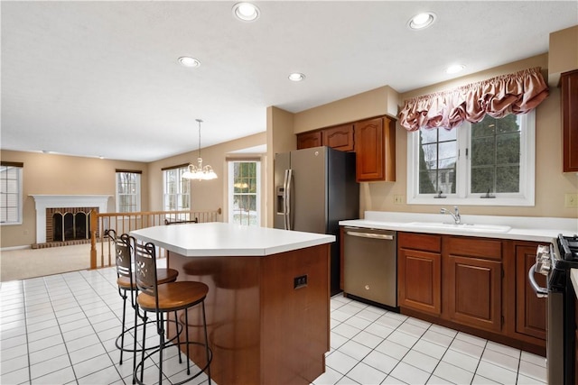 kitchen featuring a kitchen island, a breakfast bar, a sink, stainless steel appliances, and open floor plan