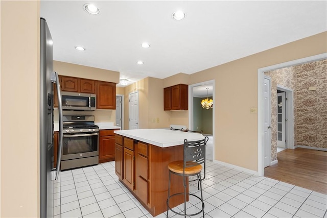 kitchen featuring a kitchen island, a kitchen bar, light countertops, light tile patterned floors, and stainless steel appliances