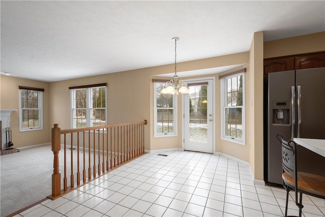 dining area with a notable chandelier, a fireplace, light tile patterned floors, baseboards, and light colored carpet