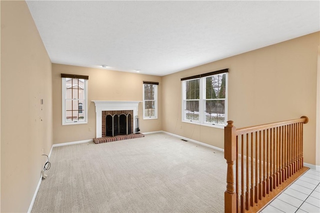 unfurnished living room with a brick fireplace, baseboards, and carpet floors