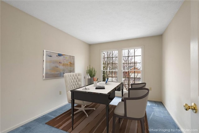 carpeted dining space featuring a textured ceiling and baseboards