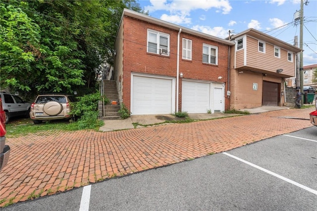 view of front of property featuring stairway, brick siding, and an attached garage