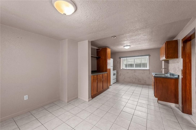 kitchen with light tile patterned floors, brown cabinetry, open shelves, freestanding refrigerator, and dark countertops