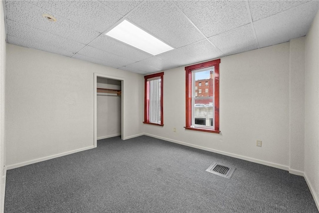 unfurnished bedroom with a closet, visible vents, dark carpet, and baseboards