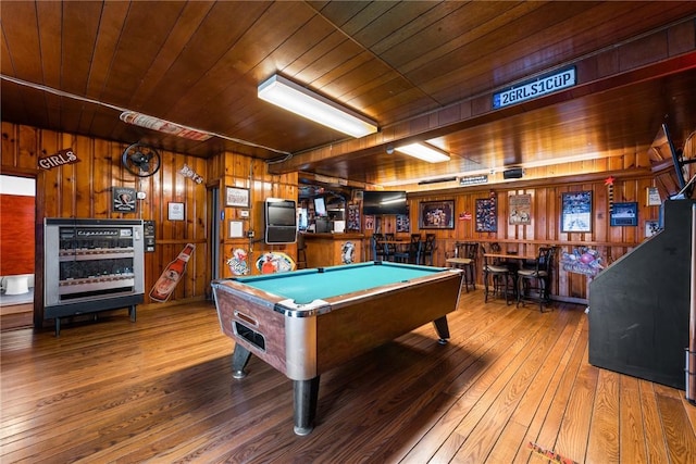 rec room featuring wood-type flooring, a bar, wood ceiling, and wooden walls