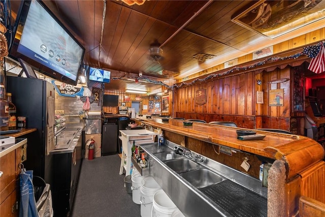 kitchen featuring a sink, wooden walls, and wooden ceiling