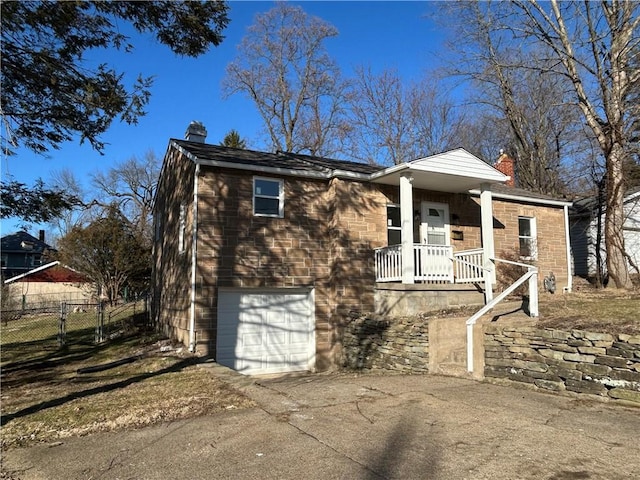 view of front of house featuring an attached garage, fence, a porch, a chimney, and driveway