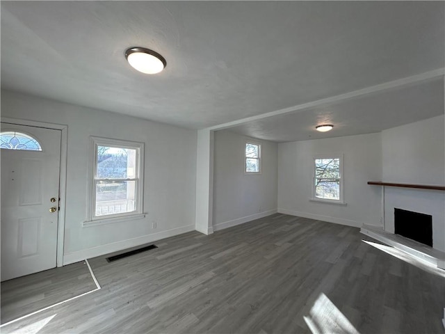 entrance foyer featuring visible vents, a fireplace with raised hearth, baseboards, and wood finished floors