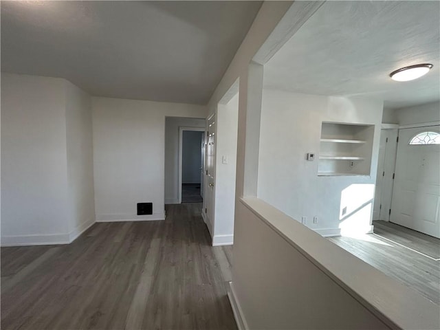 corridor with built in shelves, baseboards, and wood finished floors