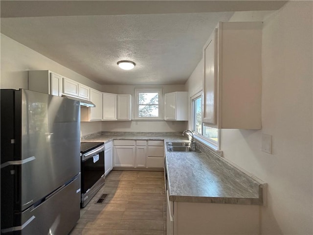 kitchen featuring freestanding refrigerator, electric range oven, a sink, white cabinets, and under cabinet range hood