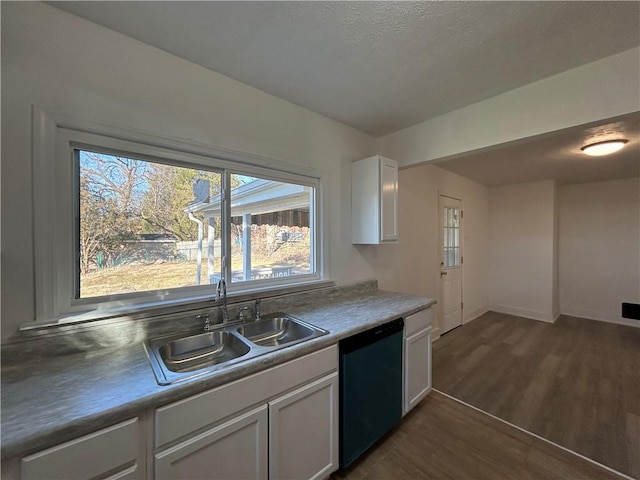 kitchen with dark wood-type flooring, a sink, white cabinets, baseboards, and dishwasher