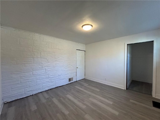 unfurnished bedroom with dark wood-style floors, visible vents, and baseboards