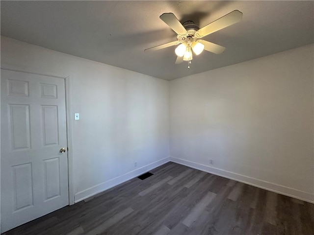 empty room with dark wood finished floors, visible vents, a ceiling fan, and baseboards