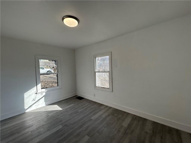 unfurnished room featuring baseboards and dark wood-style flooring