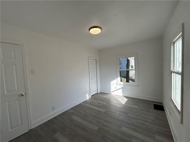 spare room with visible vents, baseboards, and dark wood-style floors