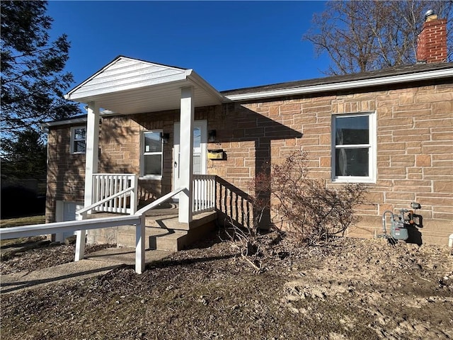 entrance to property featuring brick siding and a chimney