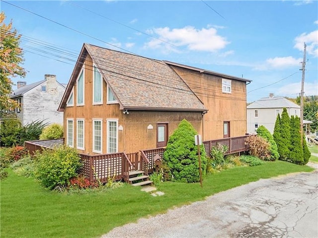 back of property with a yard and a shingled roof