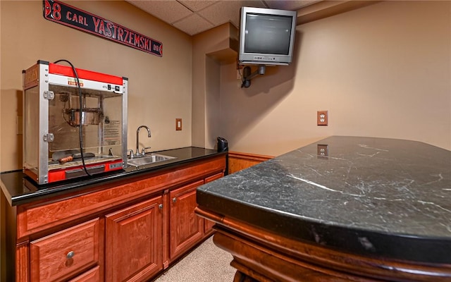 kitchen with dark countertops, carpet flooring, a drop ceiling, and a sink