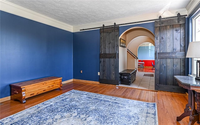 bedroom with crown molding, a barn door, and wood finished floors