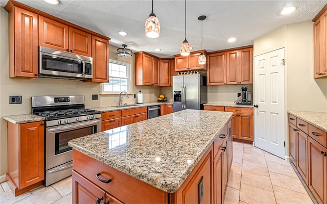 kitchen featuring light stone countertops, a kitchen island, a sink, appliances with stainless steel finishes, and brown cabinets