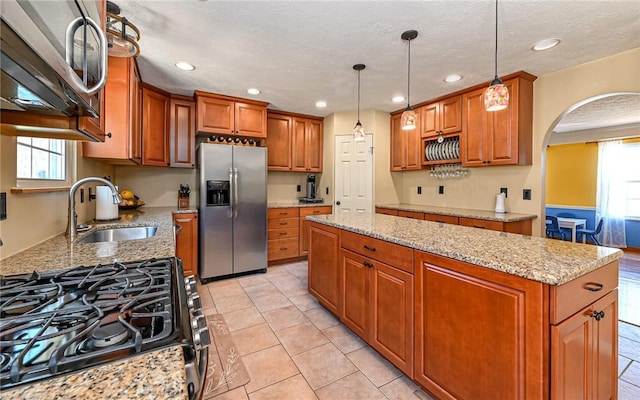 kitchen featuring a center island, brown cabinets, appliances with stainless steel finishes, and a sink