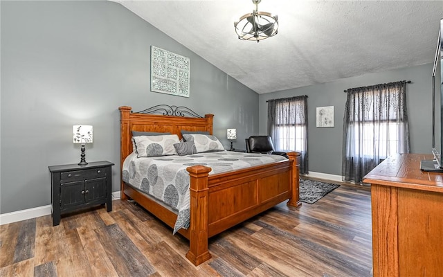 bedroom featuring a textured ceiling, baseboards, dark wood-type flooring, and lofted ceiling