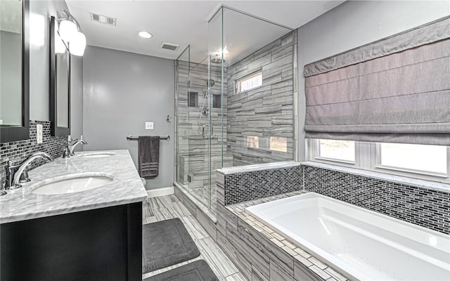 bathroom with a sink, visible vents, plenty of natural light, and a garden tub