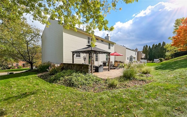 rear view of property featuring a gazebo, a yard, a chimney, and a patio area