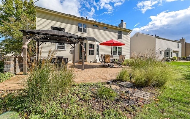 back of property with a standing seam roof, a gazebo, metal roof, a chimney, and a patio area