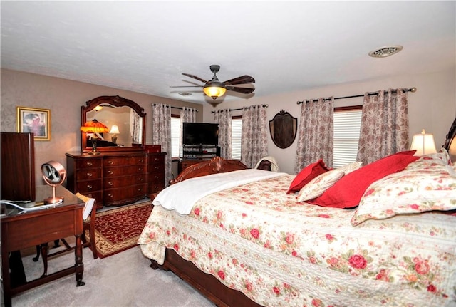 carpeted bedroom featuring visible vents, multiple windows, and ceiling fan