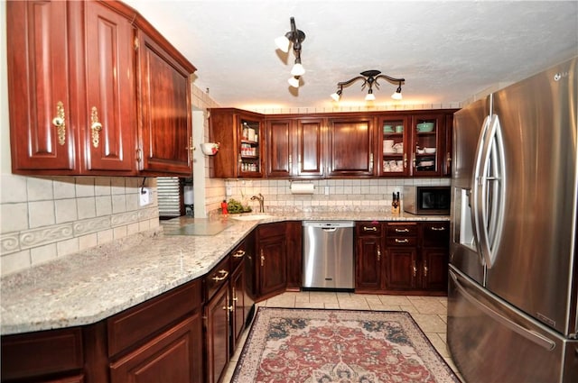 kitchen with decorative backsplash, appliances with stainless steel finishes, a sink, and light tile patterned floors