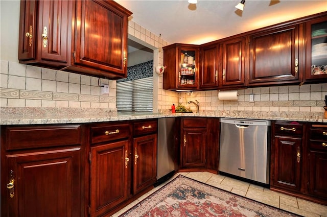 kitchen featuring light stone counters, tasteful backsplash, stainless steel dishwasher, and dark brown cabinets