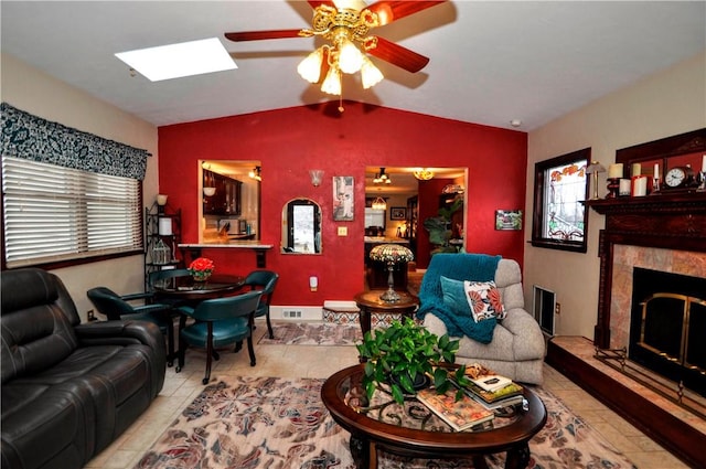 living room featuring lofted ceiling with skylight, plenty of natural light, a ceiling fan, and a premium fireplace