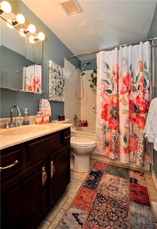 full bath featuring tile patterned floors, vanity, visible vents, toilet, and shower / bath combo with shower curtain