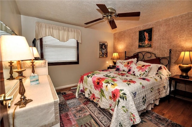 bedroom with ceiling fan, baseboards, wood finished floors, and a textured ceiling