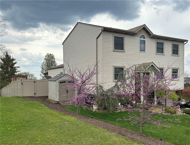view of home's exterior with a gate, fence, a storage unit, and a lawn