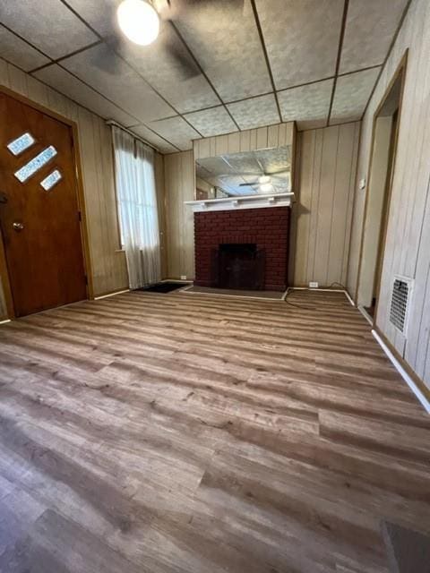 unfurnished living room with wood finished floors, a fireplace, and wood walls