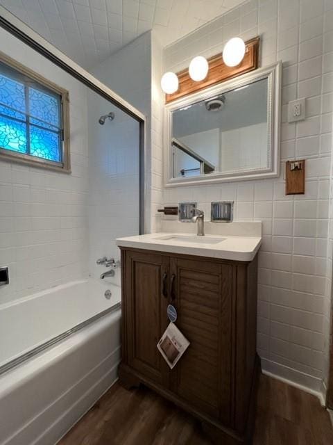 bathroom with vanity, tile walls, bathing tub / shower combination, and wood finished floors