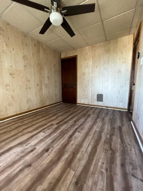 spare room featuring visible vents, a drop ceiling, a ceiling fan, and wood finished floors